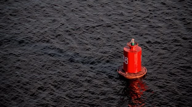 Red buoy floating on dark, rippled water