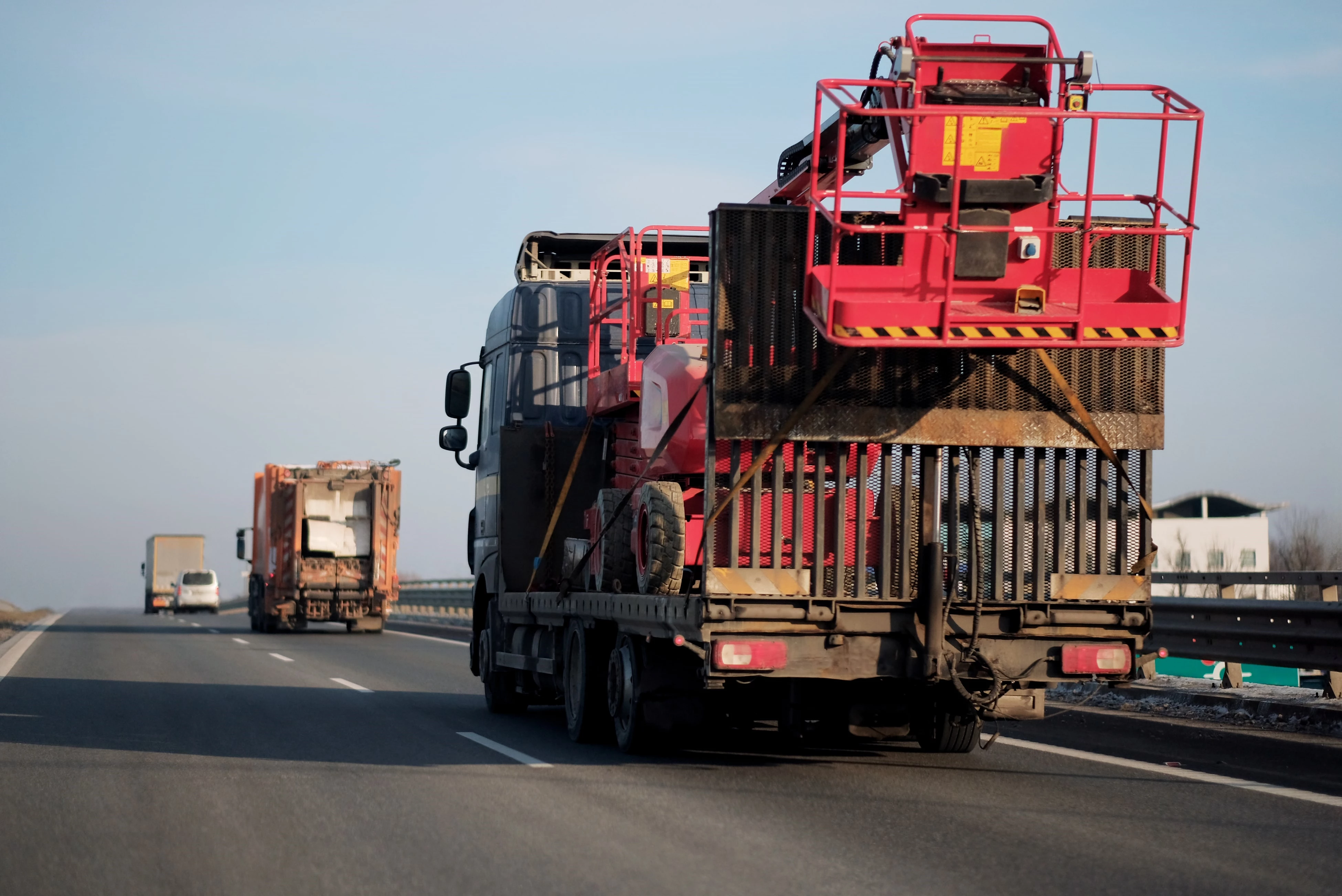 Lastbil som transporterar bred last på motorväg, tillsammans med andra fordon i trafik.
